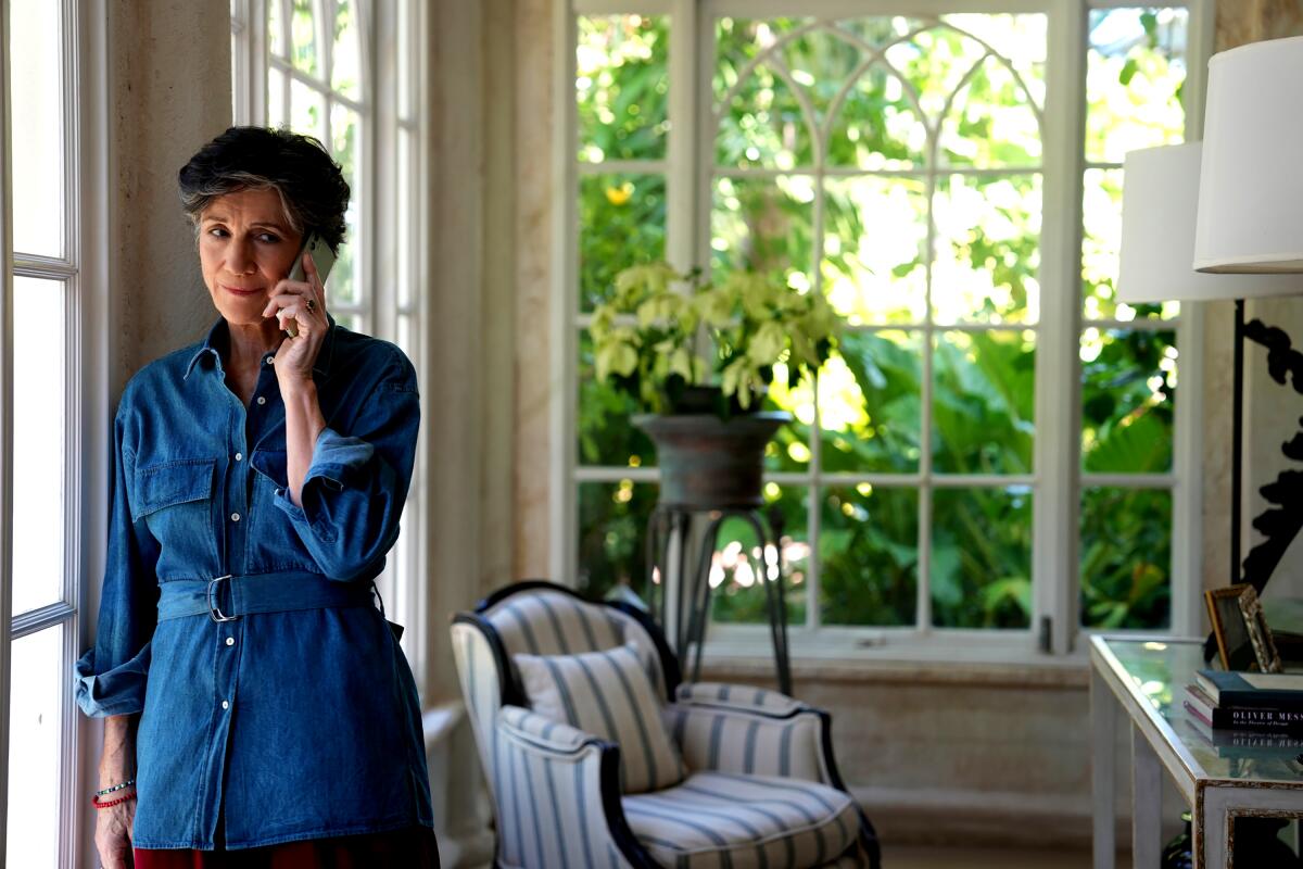 A woman stands by French doors talking on the phone in "Succession."