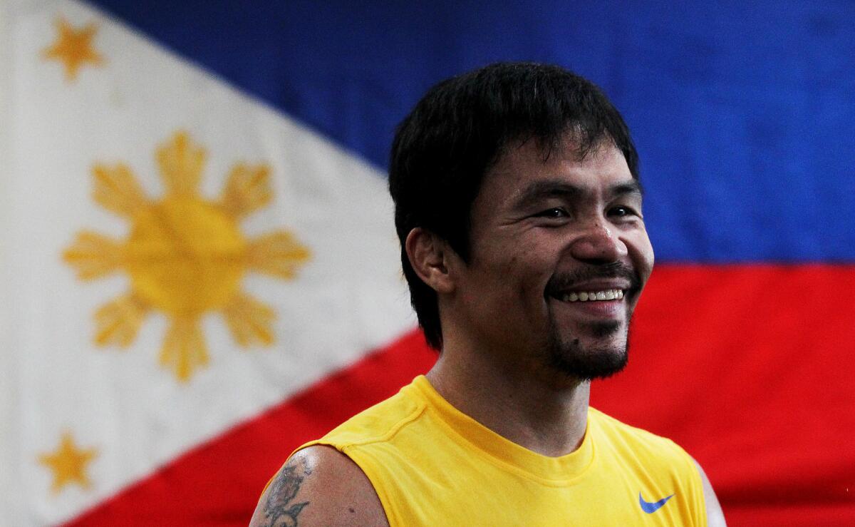 Boxer Manny Pacquiao smiles while being framed by the flag of the Philippines. He opened training camp at the Wild Card Boxing Gym in Los Angeles on Monday.