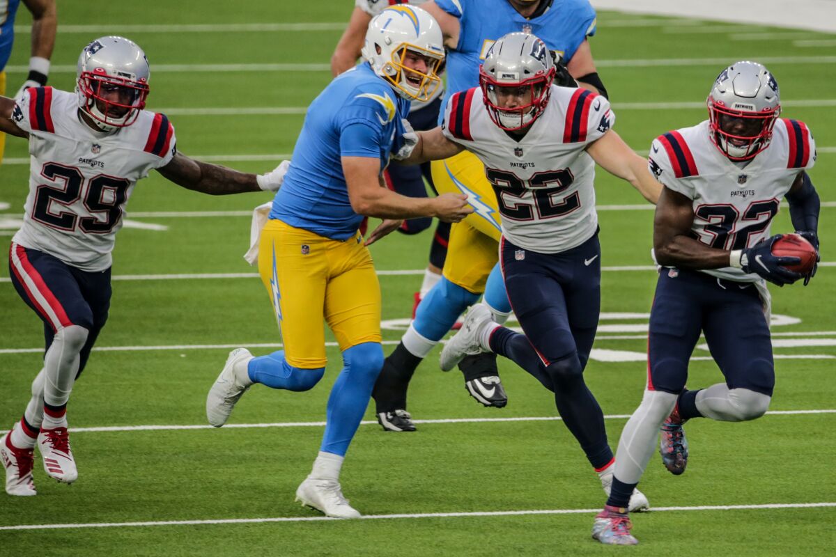 New England Patriots safety Devin McCourty scoops up a blocked field-goal attempt as the Chargers' Ty Long gives chase.