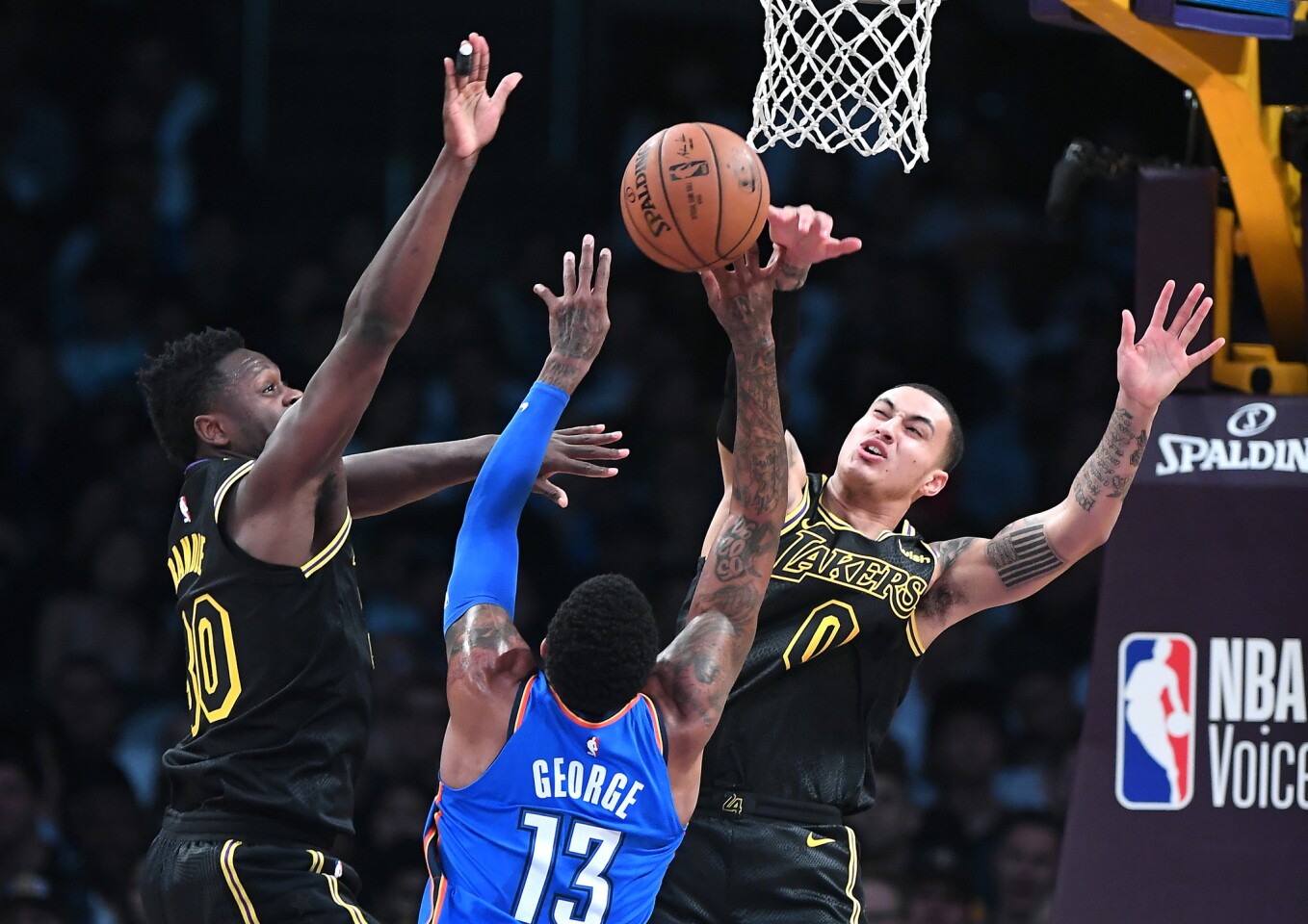 Lakers forward Kyle Kuzma, right, blocks a shot from Thunder forward Paul George as Julius Randle helps on defense during a game Thursday at Staples Center.