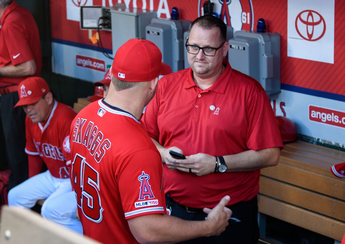 Mike Trout of the Angels, left, speaks to Eric Kay in the dugout.