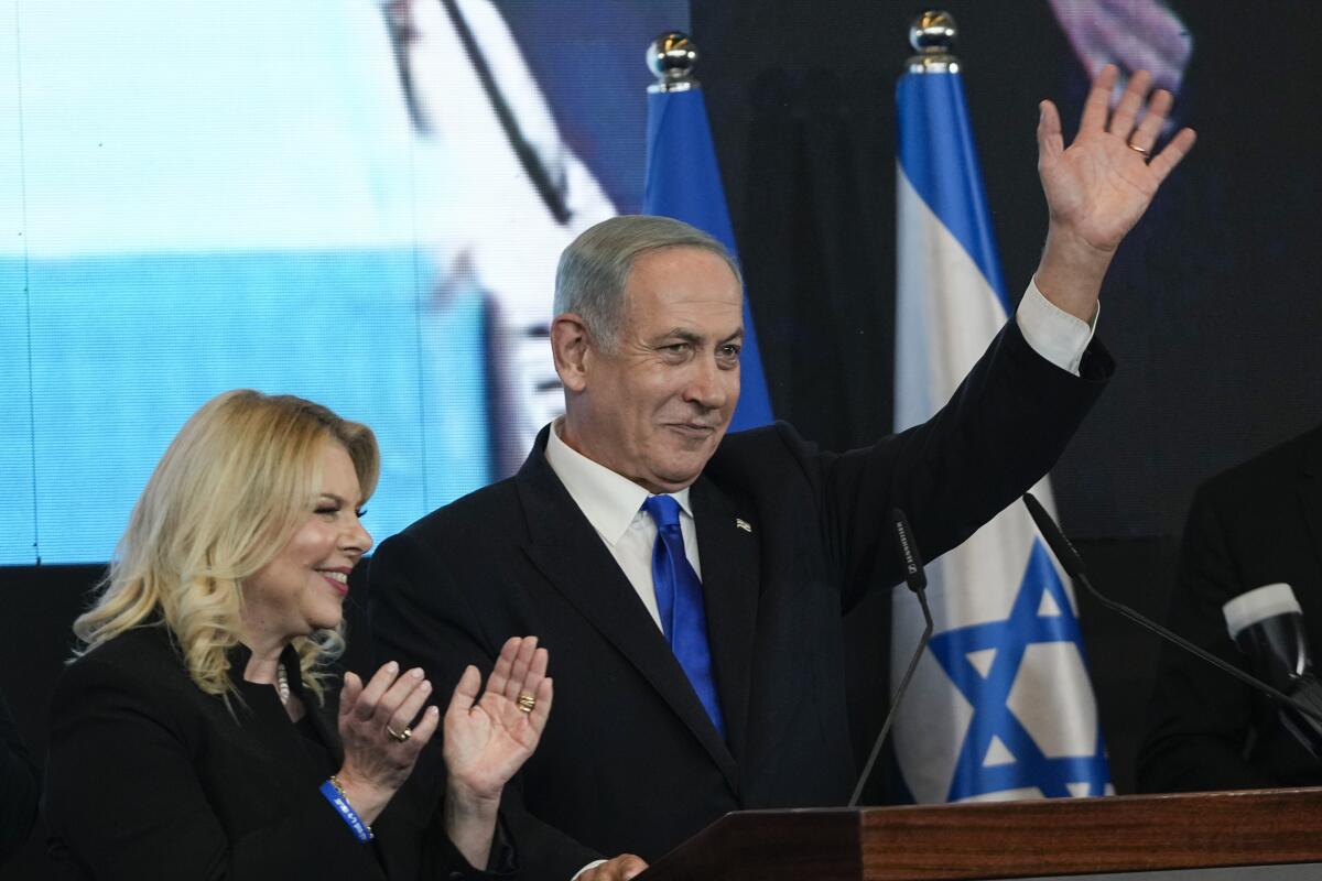 Benjamin Netanyahu waves as his wife, Sara, claps