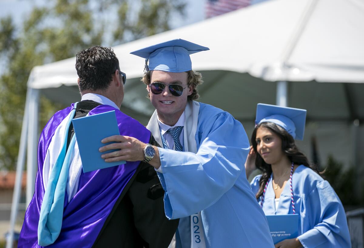 Principal Jacob Haley, left, hugs ASB President TJ Rokos after receiving his diploma.