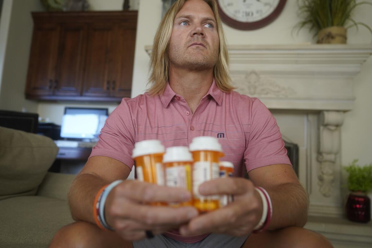David Stringham holds a cluster of prescription bottles.