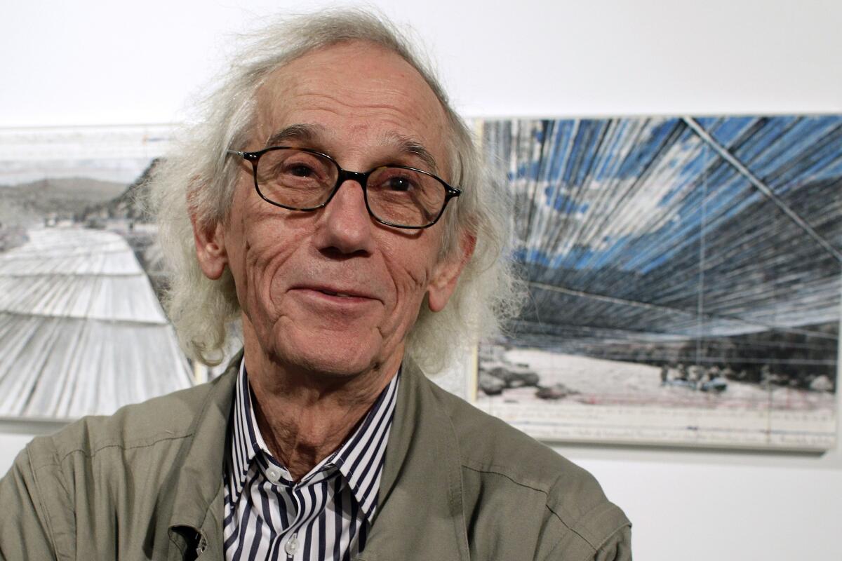 A file photo from 2013 shows artist Christo posing in front of his proposed "Over the River" project in Denver. 