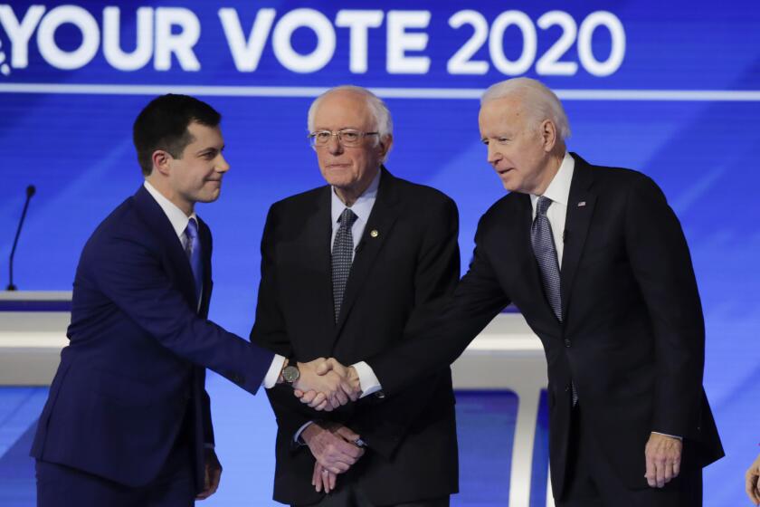 From left, Democratic presidential candidates former South Bend Mayor Pete Buttigieg, shakes hands with former Vice President Joe Biden as Sen. Bernie Sanders, I-Vt., watches Friday, Feb. 7, 2020, before the start of a Democratic presidential primary debate hosted by ABC News, Apple News, and WMUR-TV at Saint Anselm College in Manchester, N.H. (AP Photo/Charles Krupa)