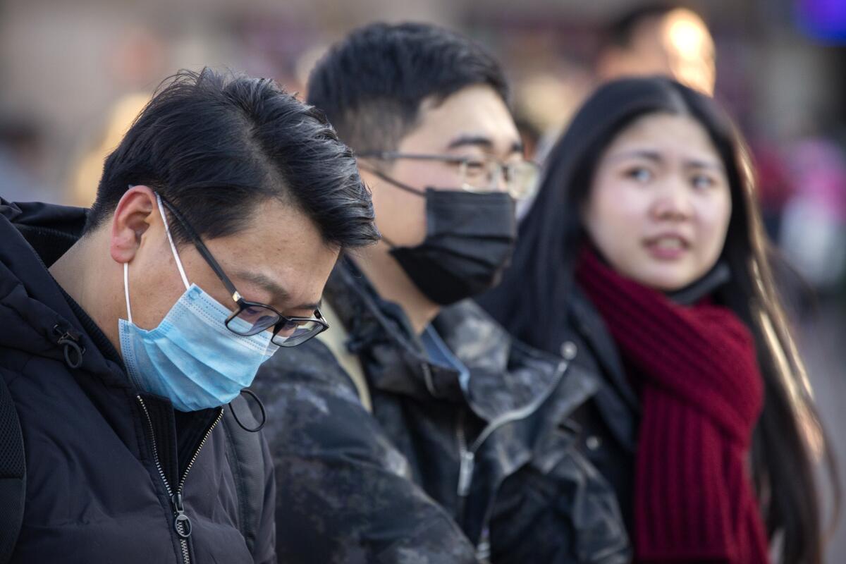 Travelers wear masks in Beijing, where anxiety rose after it was confirmed that the coronavirus can spread from human to human.