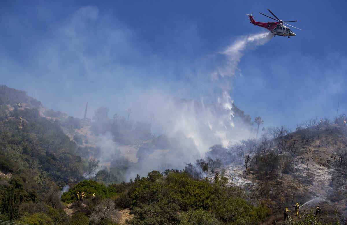 A helicopter drops water on a brushfire in the Hollywood Hills in 2020. 