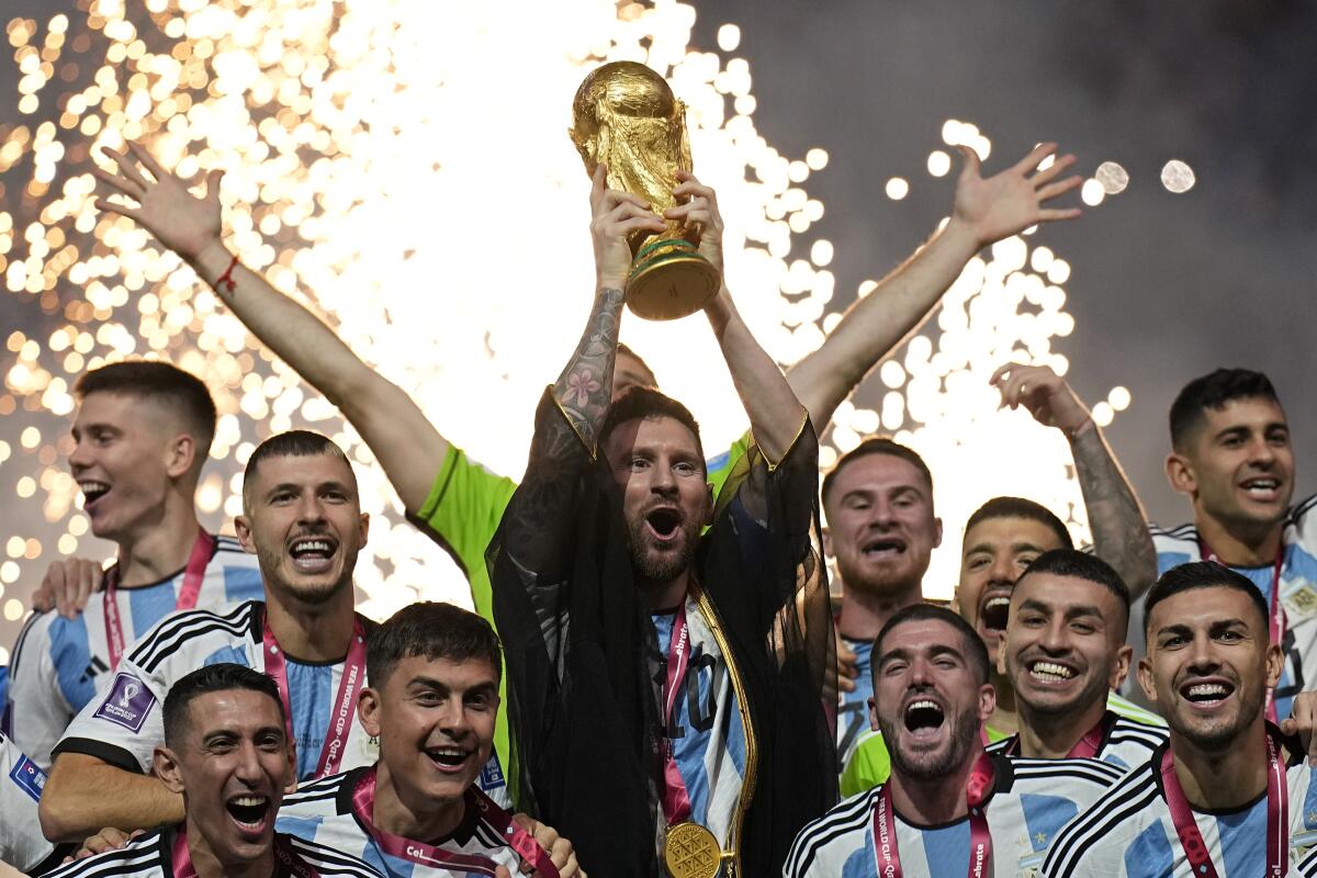 Argentina's Lionel Messi lifts the trophy while surrounded by teammates.