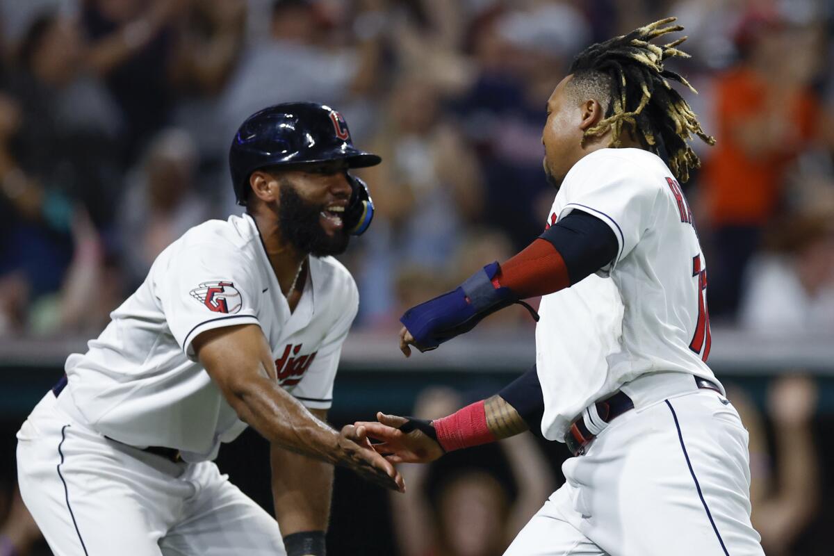 Cleveland Guardians' Amed Rosario. left, and Jose Ramirez celebrate after scoring on a single by Andres Gimenez during the seventh inning of a baseball game against the Chicago White Sox, Friday, Aug. 19, 2022, in Cleveland. (AP Photo/Ron Schwane)