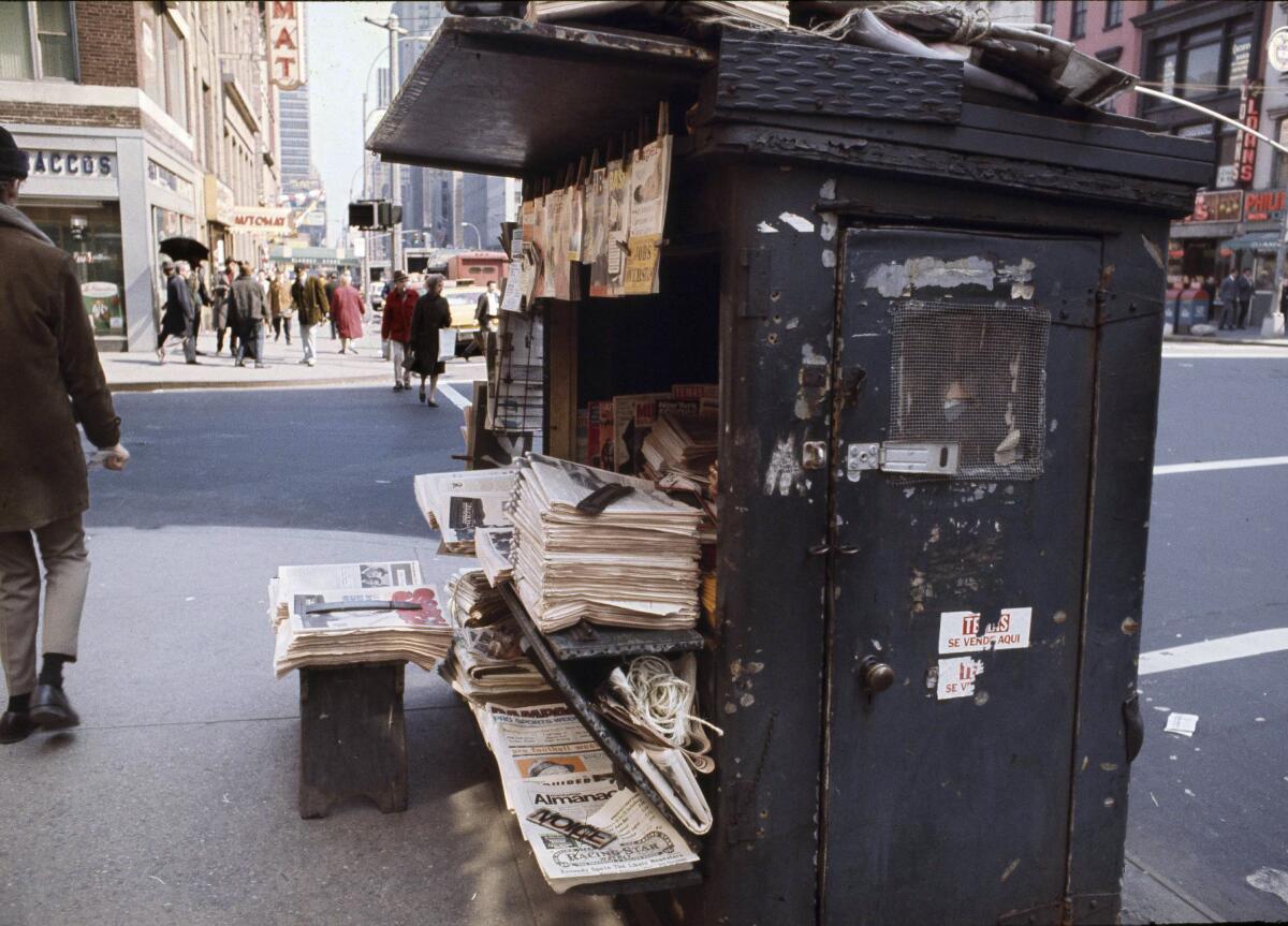 Bundles of newspapers are stacked up at a newsstand