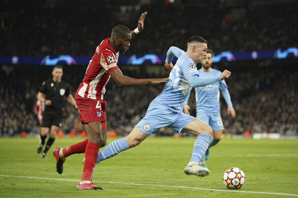 Manchester City's Phil Foden, right, is challenged by Atletico Madrid's Geoffrey Kondogbia during the Champions League, first leg, quarterfinal soccer match between Manchester City and Atletico Madrid at the Etihad Stadium, in Manchester, Tuesday, April 5, 2022. (AP Photo/Dave Thompson)