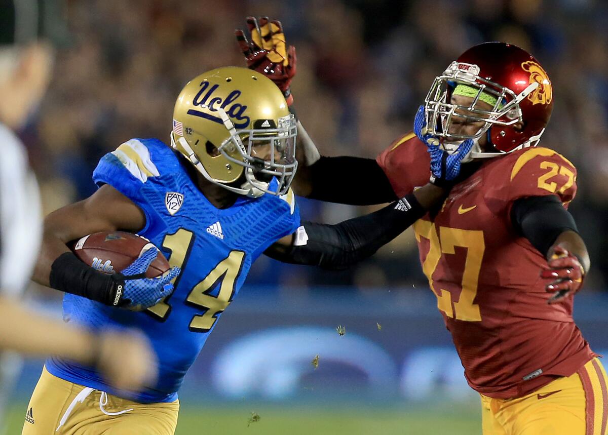 UCLA receiver Mossi Johnson puts his hand into the face of USC safety Gerald Bowman on a catch and run in the third quarter Saturday night at the Rose Bowl. The Bruins beat the Trojans, 38-20.