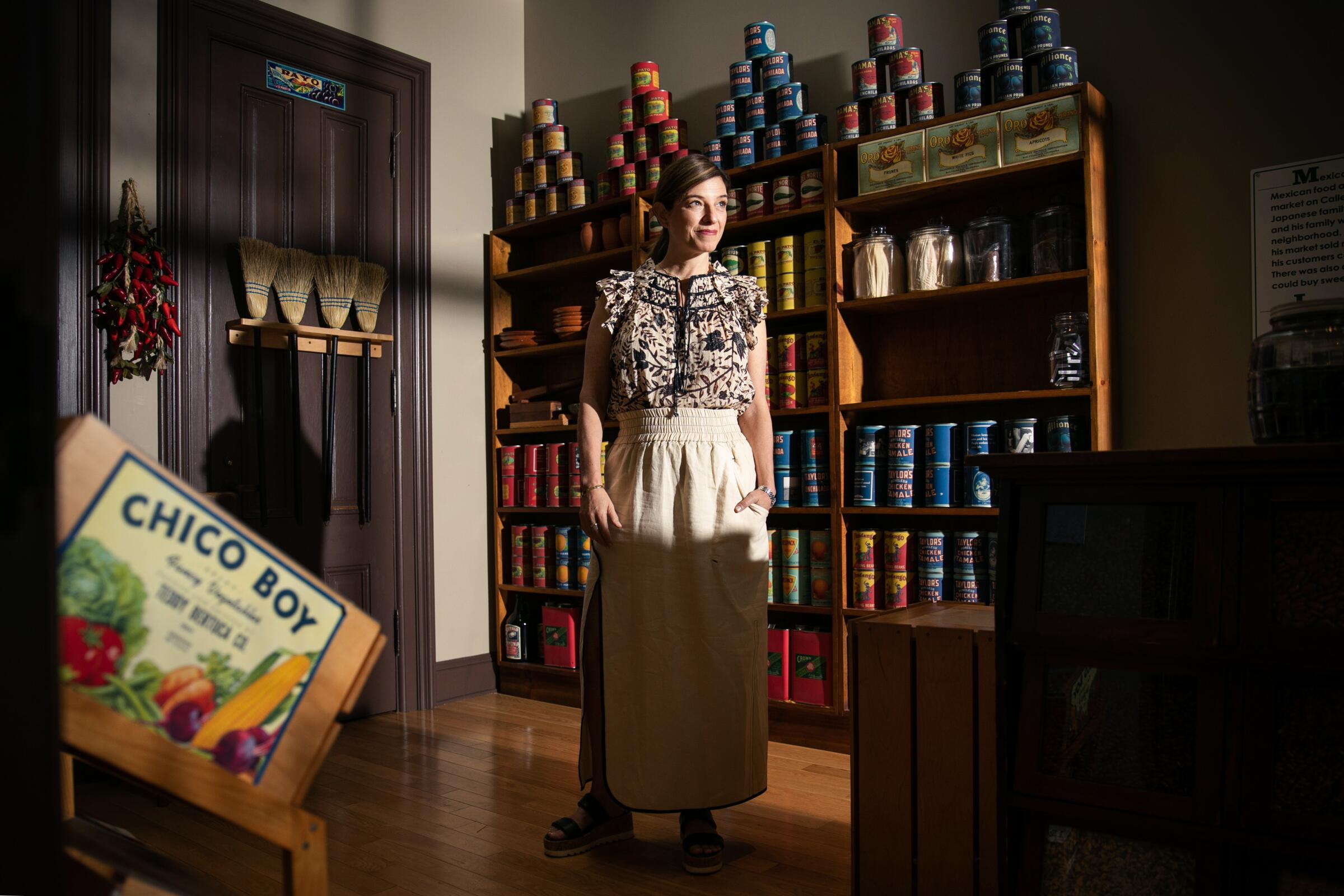 Chef Pati Jinich stands in front of a wall of canned goods.