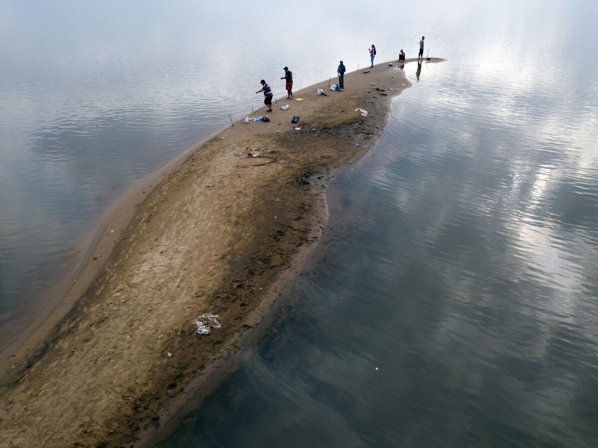Men fish from a sand bank on the Paraguay River, taking advantage of the historical drop of water levels in San Antonio, Paraguay, on the outskirts of Asuncion, on Thursday, Oct. 15, 2020. (Ap Photo/Jorge Saenz)