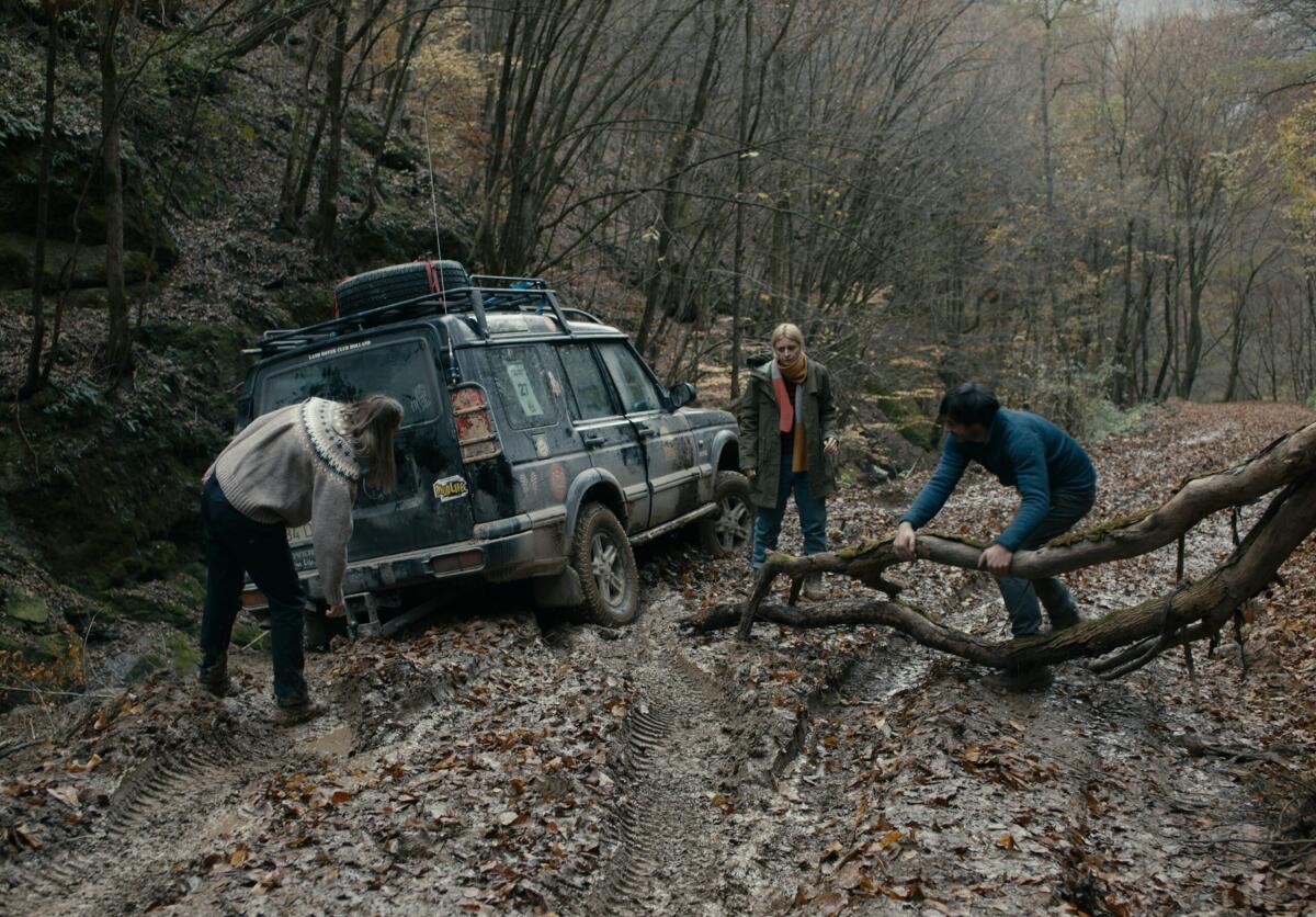 People stand around a car stuck in the mud in a scene from the movie "Întregalde."