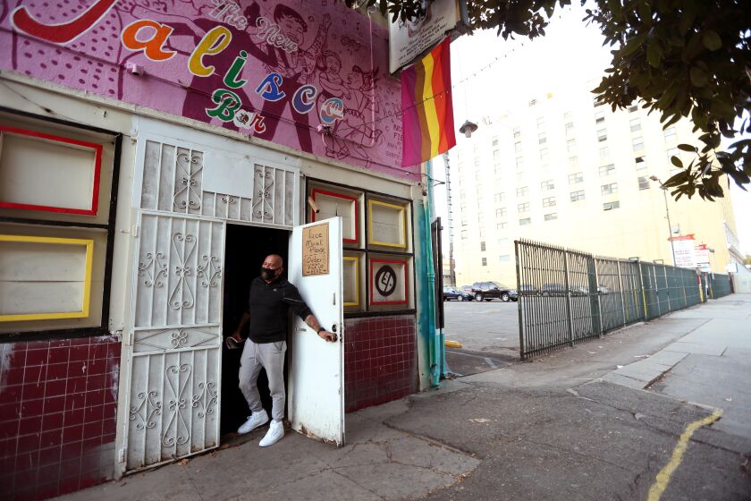 LOS ANGELES, CA - JANUARY 14, 2021 - Sergio Hernandez, co-owner of the New Jalisco bar, looks out the front door of the closed establishment during the ongoing coronavirus pandemic in downtown Los Angeles on January 14, 2021. The bar has been a lifeline for LGBTQ Latinos and is on the brink of permanent closure. Before the pandemic the bar was an institution catering to the Latino LGBT community. The Hernandez' are now 10 months behind in rent and would need $80,000 to reopen. An online fundraiser has raised more than $30,000. The couple now sell tacos outside their home in south-central nightly from 6 pm onward to make ends meet. Some of the drag queens who worked at the bar visit them for tacos a couple times a week. Genaro Molina / Los Angeles Times)