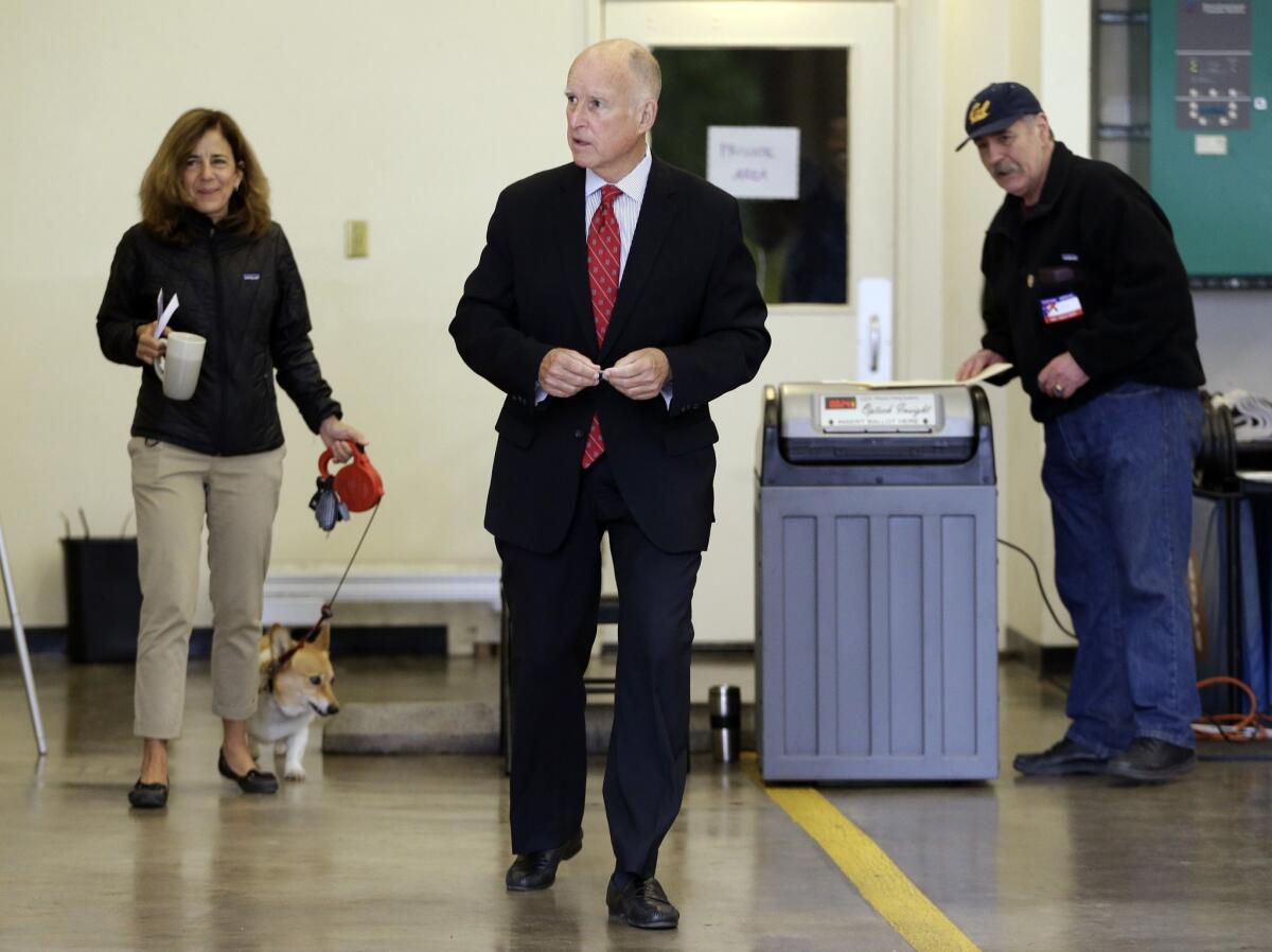 California Gov. Jerry Brown leaves a polling area after casting his vote Tuesday in Oakland. At left is his wife, Anne Gust.