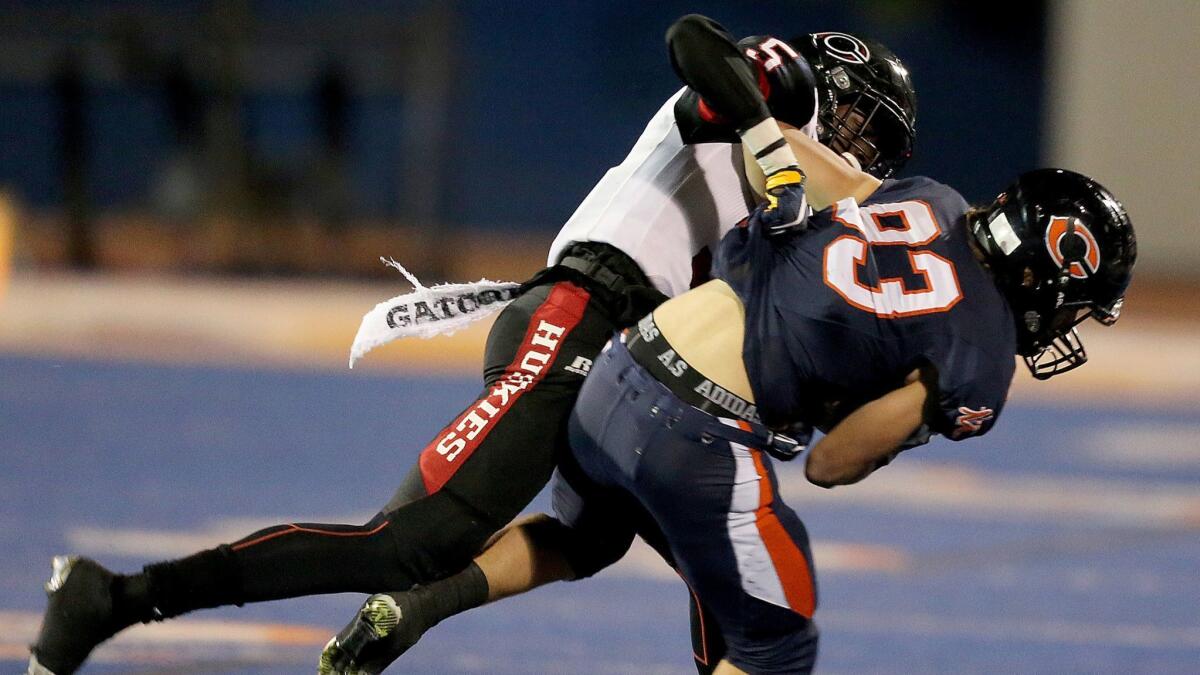 Corona Centennial defensive back Isaiah Young (left) brings down Chaminade's Owen Larson in the second half on Nov. 18, 2016, at Chaminade High in West Hills.