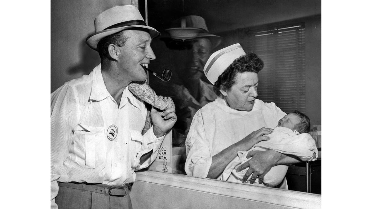 Sept. 15, 1959: Singer Bing Crosby smiles for his first and only daughter, Mary Frances, held by nurse Sadie Neal at Queen of Angels Hospital in Los Angeles.