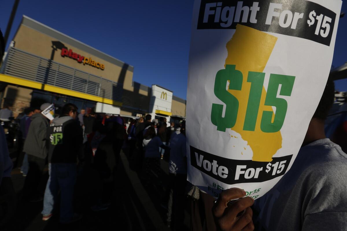 Protesters and activists carry signs and chant for higher wages in the parking lot at a McDonalds in South Los Angeles November 10, 2015. The Fight For 15 campaign is a nationwide effort to raise minimum wages and benefits at fast food restaurants. (Mark Boster/ Los Angeles Times)