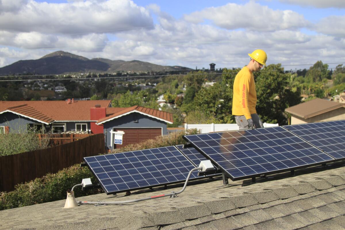 An electrician puts the finishing touches on a home rooftop solar and battery installation in El Cajon in 2019. 