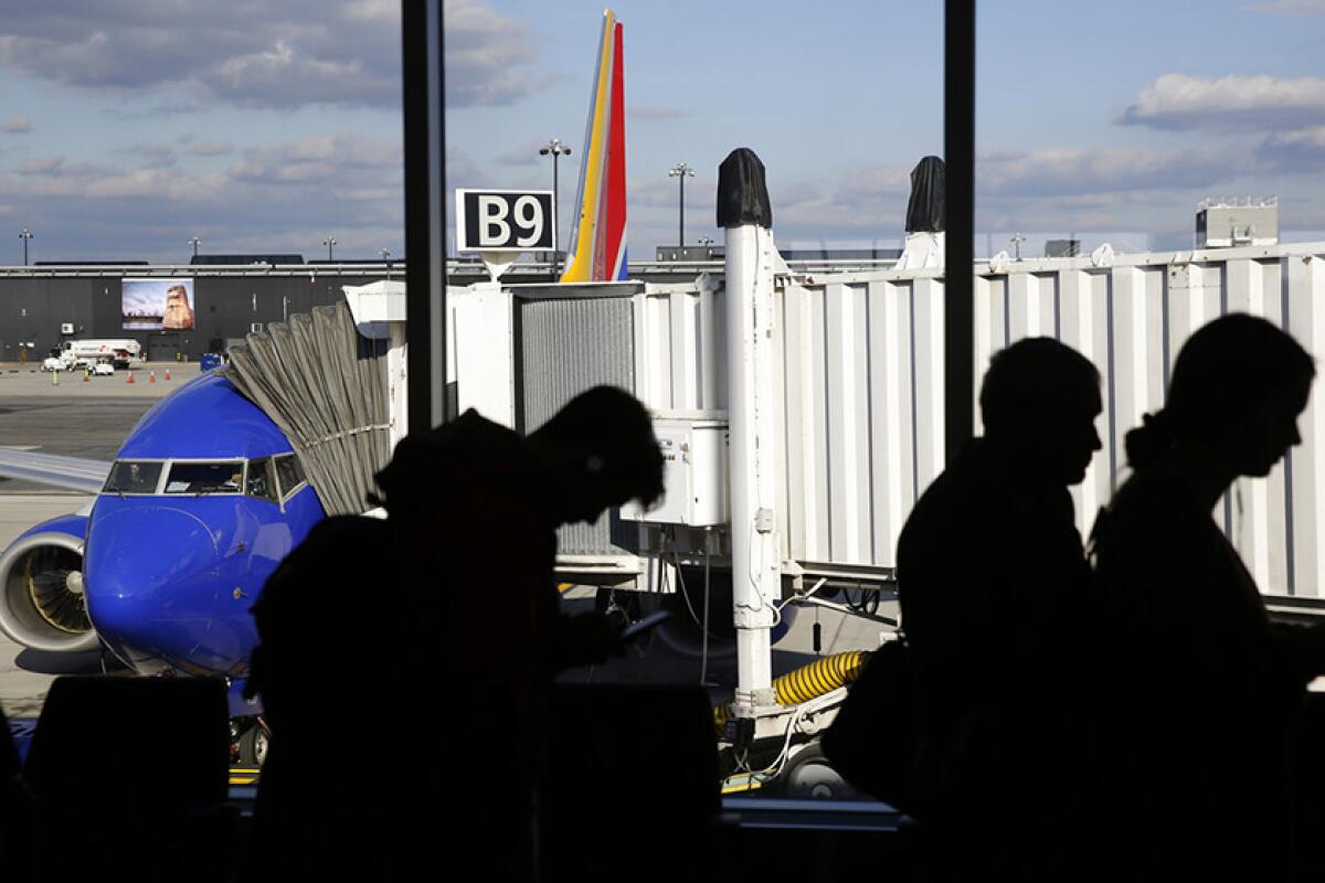 Passengers are seen in silhouette with a plane and passenger boarding bridge in the background.