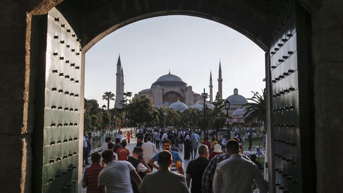 Turkish Muslims leave after Eid al-Fitr prayers at the landmark Sultan Ahmed Mosque, or Blue Mosque, in Istanbul, on June 25, 2017. The Hagia Sophia Museum, another landmark of the city, is seen in the background.