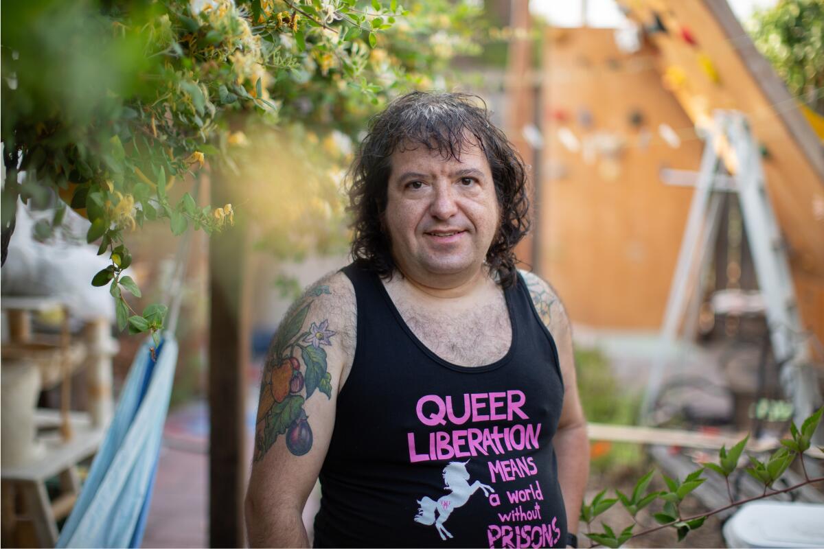 Tim Chevalier poses in a shirt that reads "Queer Liberation Means a World Without Prisons."
