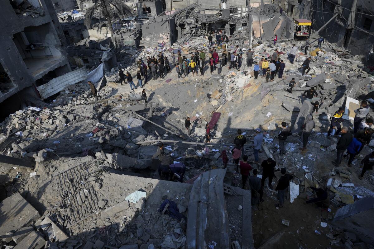 People look at the destruction of a residential building after an Israeli strike in the central Gaza Strip.