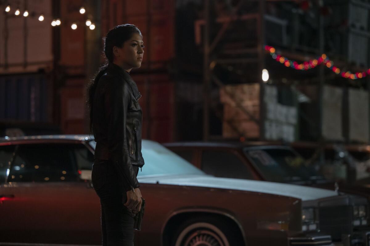 A woman standing next to a car on a dark street.