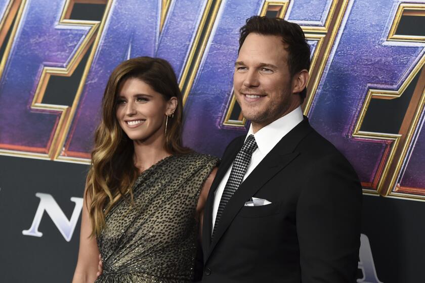 A woman in a patterned dress posing with a man in a black suit