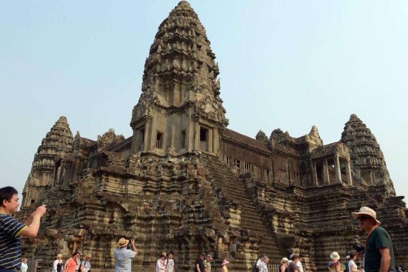 A tourist (L) takes a photo of the Angkor Wat temple in Siem Reap province on March 20, 2015. US First Lady Michelle Obama flew into Cambodia at the tourist hub of Seam Reap late March 20, becoming the first wife of a sitting US president to visit the country, part of a two-nation trip to highlight the importance of girls' education. AFP PHOTO / TANG CHHIN SOTHYTANG CHHIN SOTHY/AFP/Getty Images ORG XMIT: