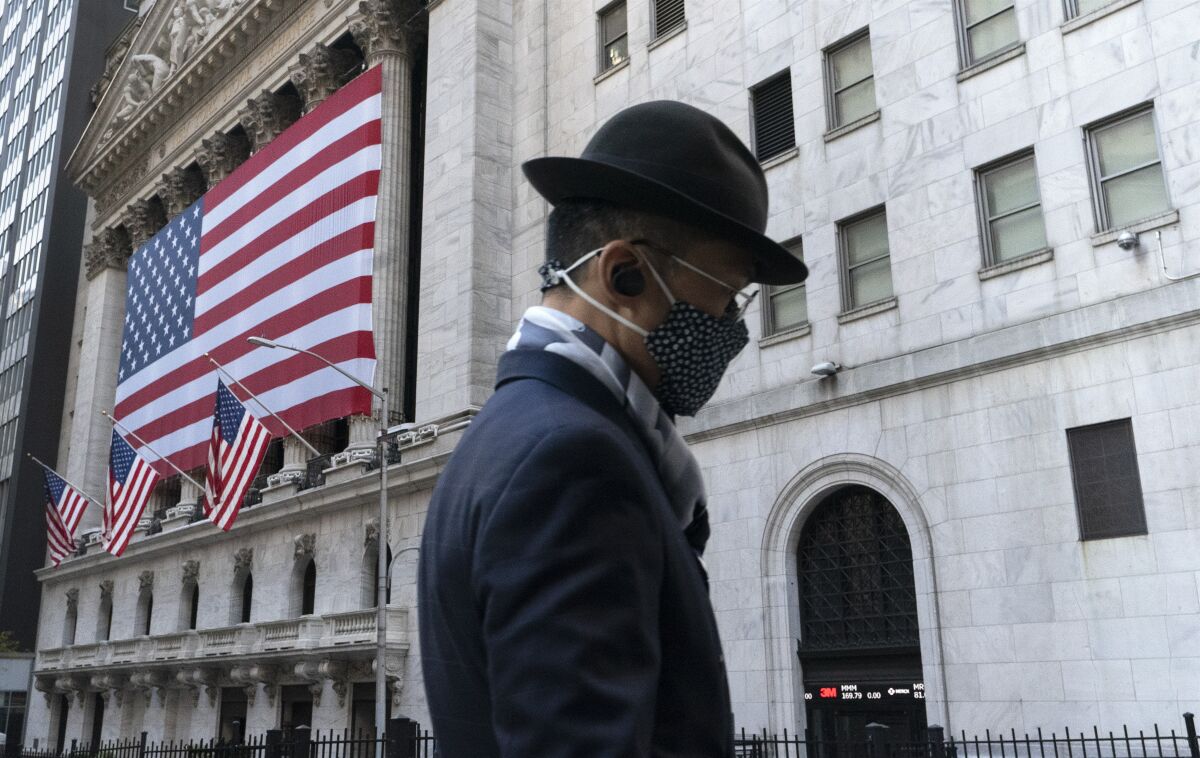 FILE - In this Nov. 16, 2020 file photo, a man wearing a mask passes the New York Stock Exchange, in New York. U.S. stocks are falling from their record highs Monday, Jan. 4, 2021, as trading gets underway in a year where the dominant expectation is for a powerful economic rebound to eventually sweep the world. (AP Photo/Mark Lennihan, File)