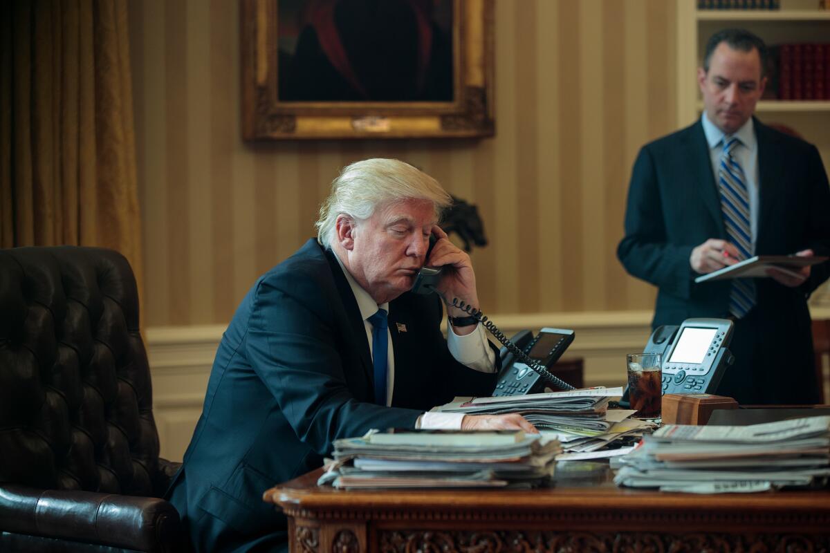 President Trump speaks by phone with Russian President Vladimir Putin in the Oval Office on Saturday as White House Chief of Staff Reince Priebus looks on.