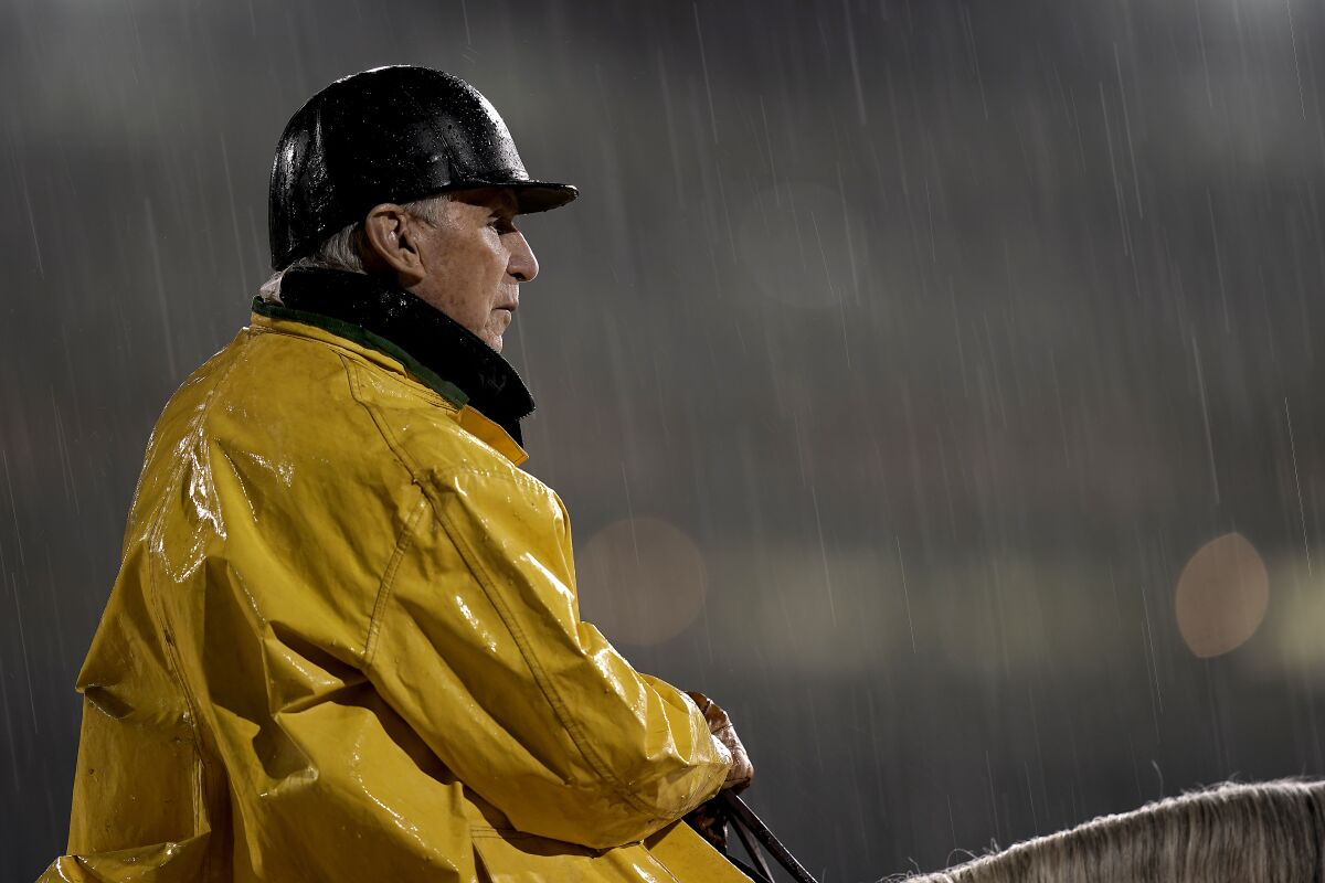 Trainer D. Wayne Lukas watches a horse workout in the rain at Churchill Downs Tuesday, May 3, 2022, in Louisville, Ky. The 148th running of the Kentucky Derby is scheduled for Saturday, May 7. (AP Photo/Charlie Riedel)