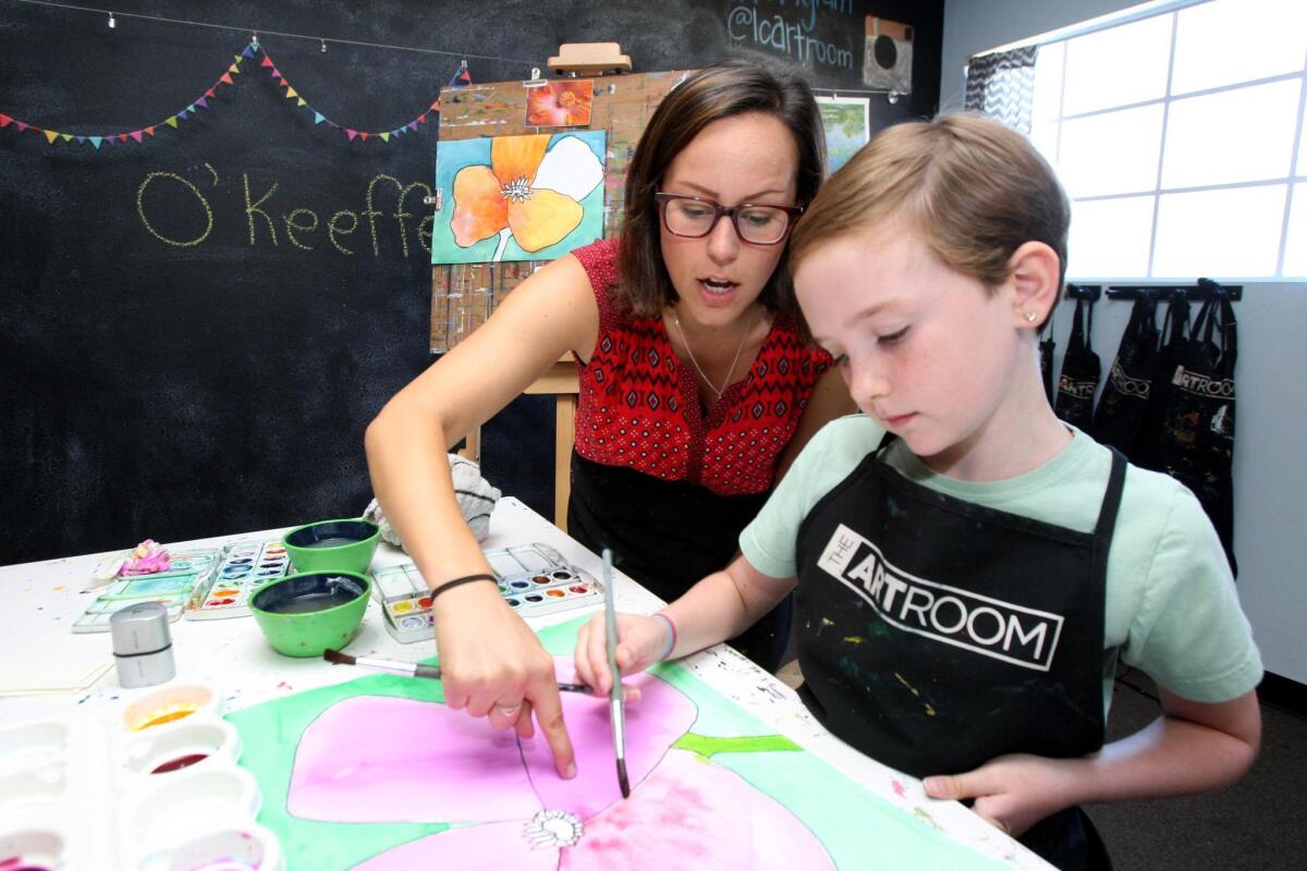 The Art Room instructor Jenna Macho shows 9-year old Tyler Frey how to create shades with watercolors.