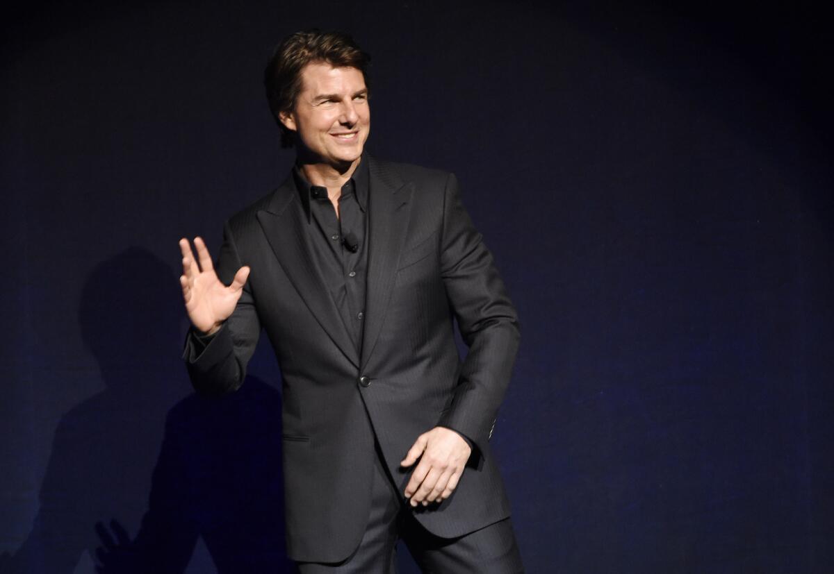 Tom Cruise, star of the upcoming film "Mission: Impossible -- Rogue Nation," waves to the audience during a surprise appearance at the Paramount Pictures presentation at CinemaCon.
