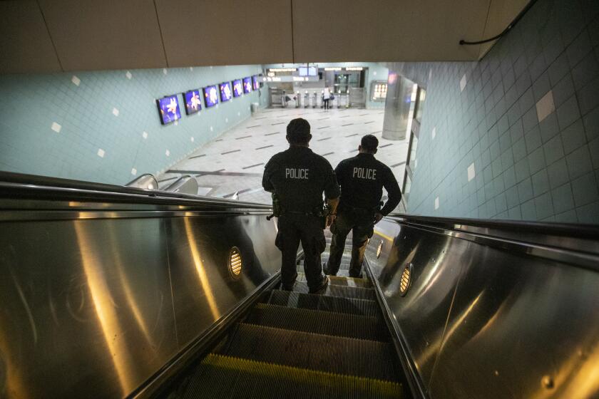 HOLLYWOOD, CA - JUNE 25: LAPD officers E. Rosales, left, and D. Castro, patrol the Metro Red Line Hollywood/Highland Metro Station as tourists pass by Thursday, June 25, 2020 in Hollywood, CA. The Metro Board of Directors held a meeting Thursday where the agenda included the consideration of appointing a committee to develop plans for replacing armed transit safety officers with ``smarter and more effective methods of providing public safety.'' Metro security is staffed by multiple agencies, including the L.A. County Sheriff's Department and L.A. and Long Beach police departments, transit security guards and contract security workers. (Allen J. Schaben / Los Angeles Times)