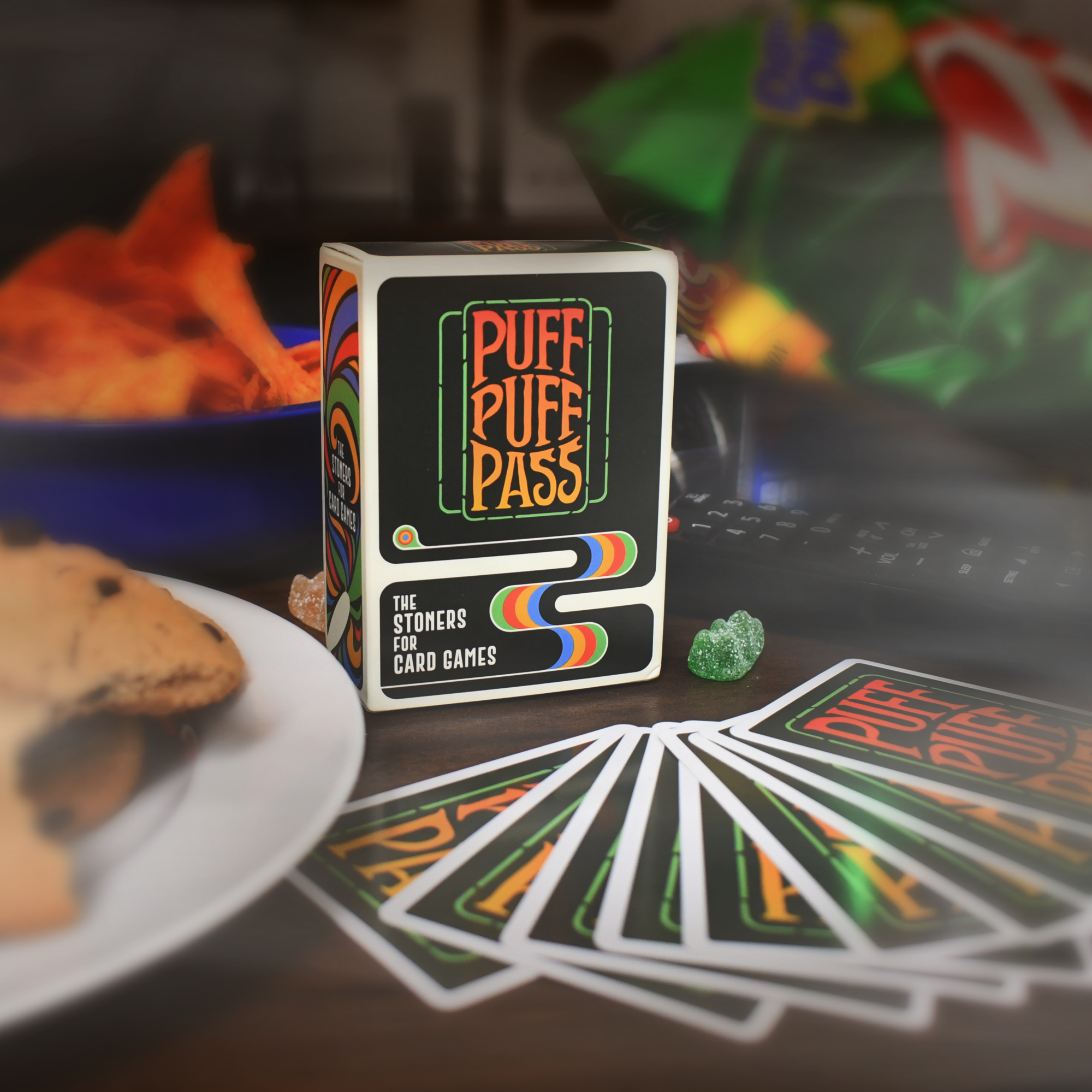 Cards from the Puff Puff Pass card game rest on a table next to cookies