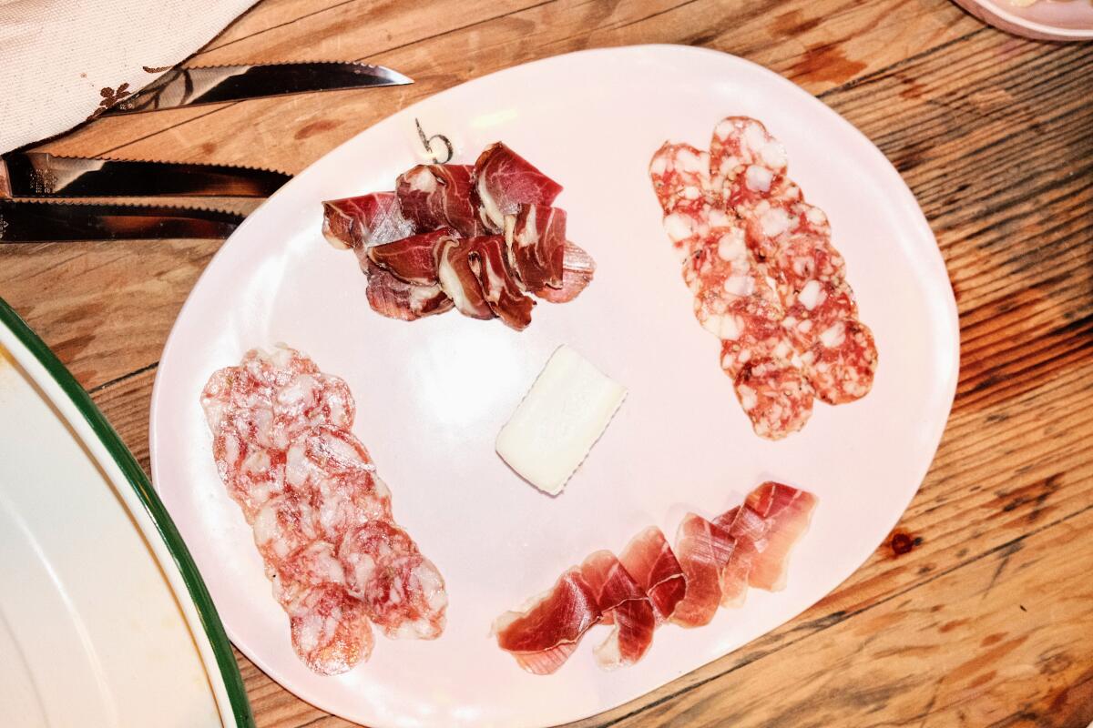 An overhead photo of four varieties of charcuterie, a slice of cheese at center, in Echo Park wine bar Butchr Bar