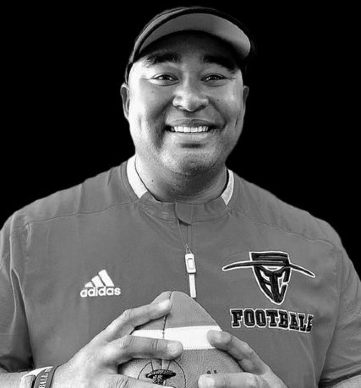 Santa Ana College football coach Anthony White poses for a photo clasping a ball in his hands.