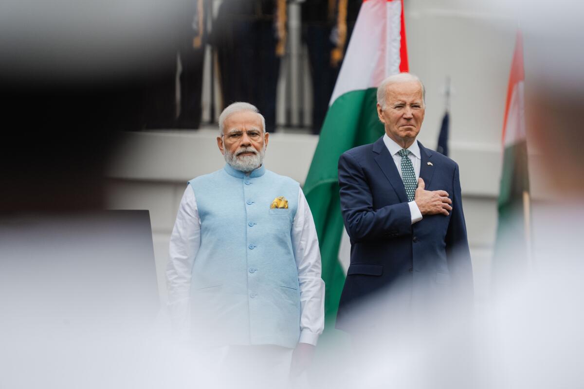President Biden standing with his right hand over his heart next to Indian Prime Minister Narendra Modi