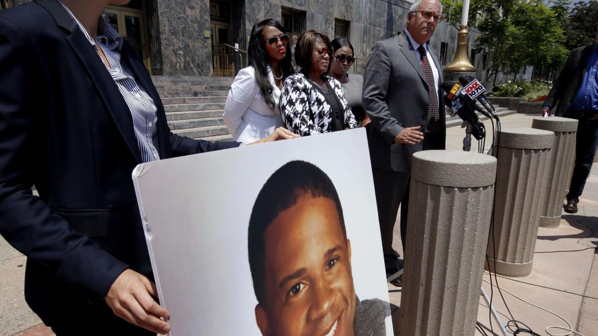 Attorney Peter Morris, right, discusses a lawsuit filed by the family of Dennis Williams-Rogers, whose photograph was displayed during the news conference.