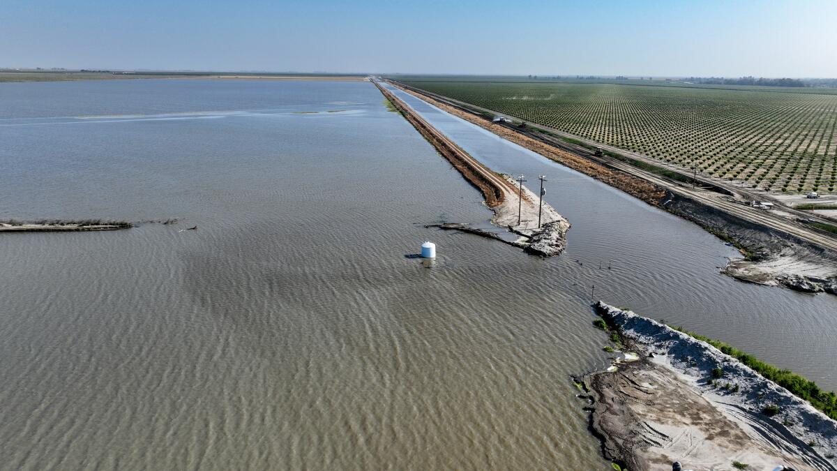 An aerial view of a breached levee at a body of water.