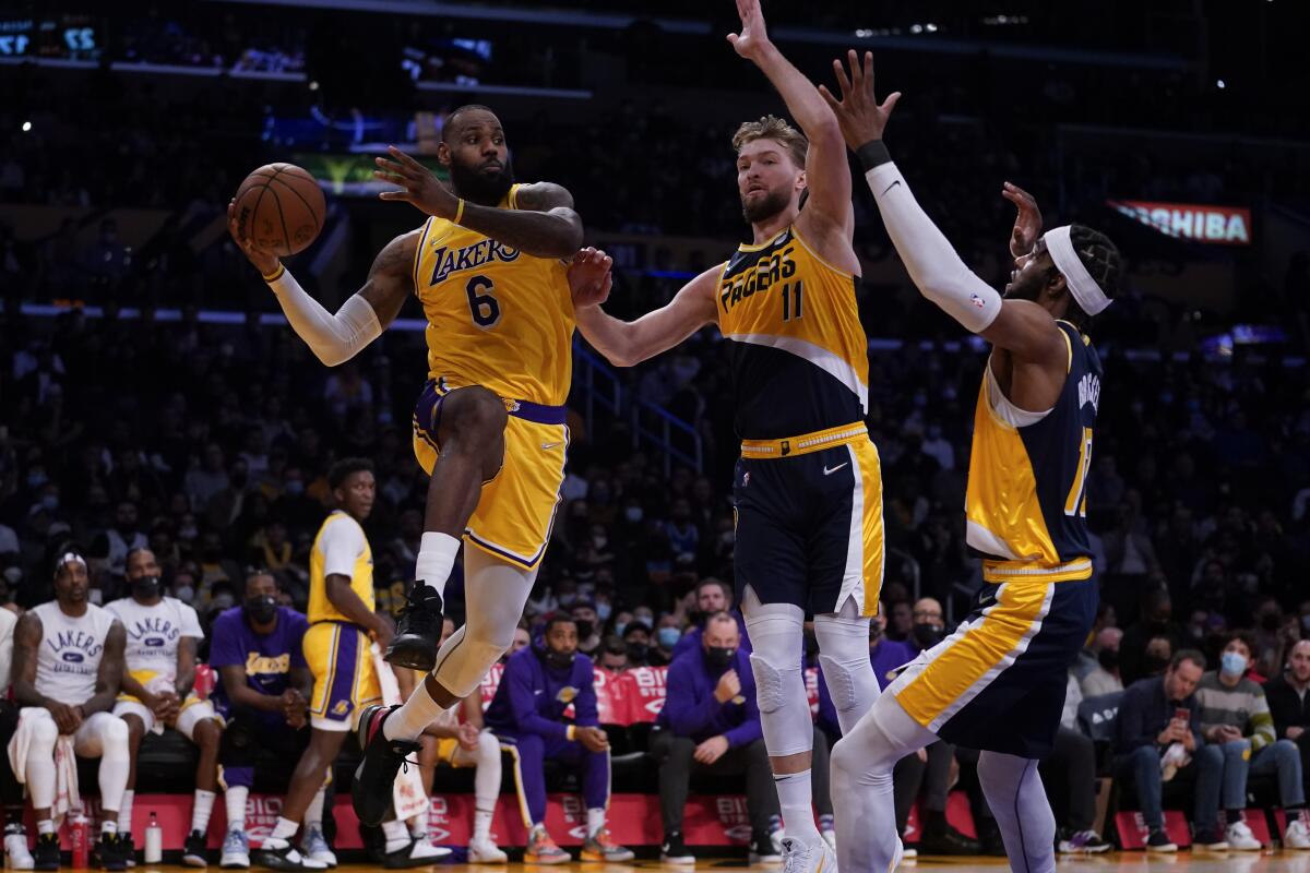 LeBron James (6), de los Lakers de los Ángeles, realiza un pase ante la presión de los jugadores de los Pacers.
