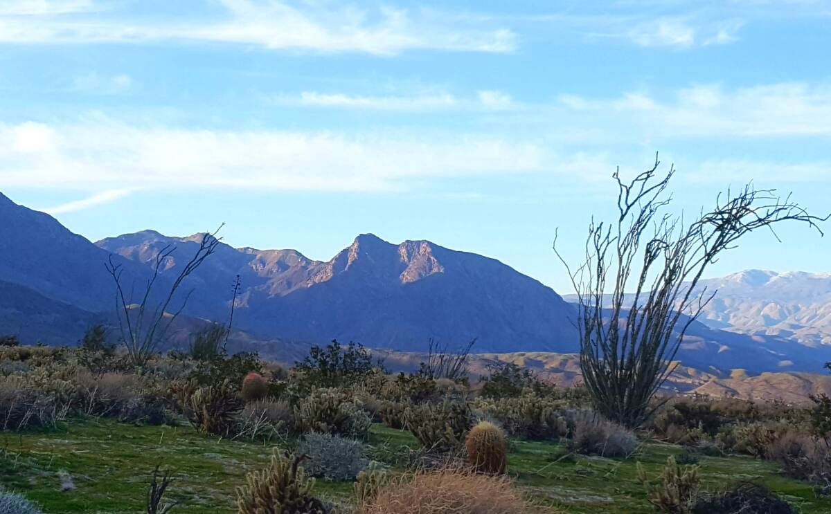 A mountainous landscape with green shrubbery and blue skies