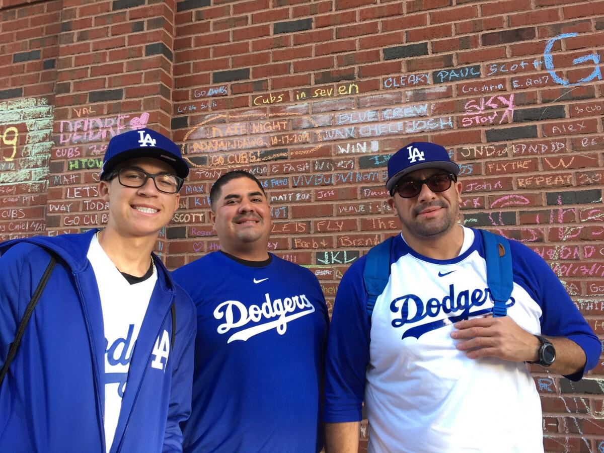 Josh Escobar, left, Juan Barrera and Miguel Escobar pose beneath their "Blue Crew" note on the Wrigley Field wall.