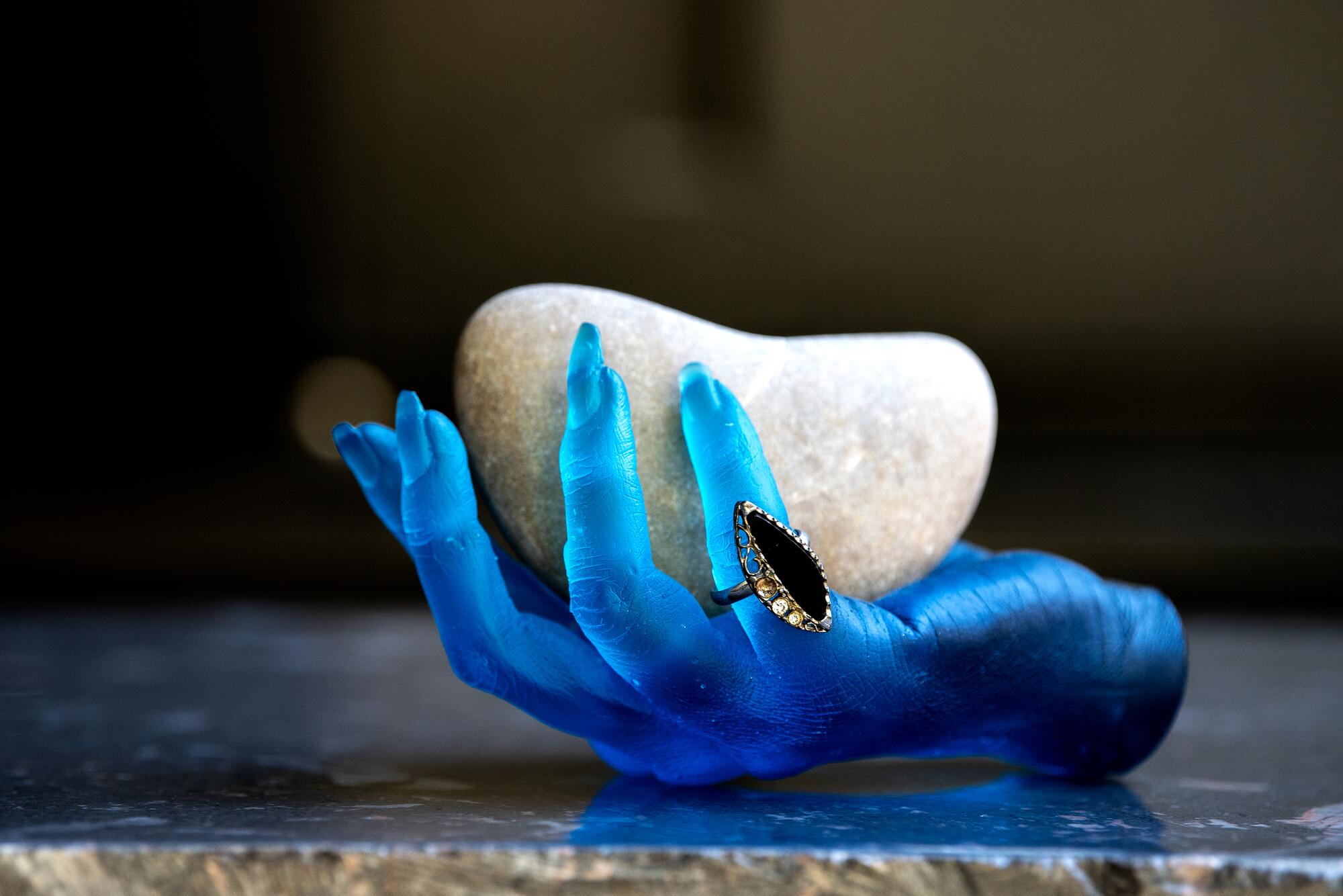 A blue sculpted hand holds a rock.