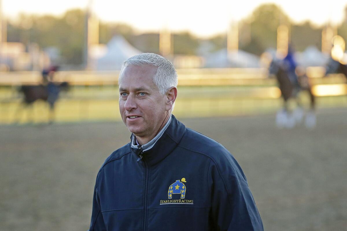 Todd Pletcher watches horses on the track at Churchill Downs.